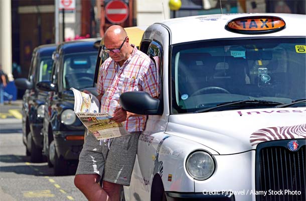 客を待つ間に「タイムズ」紙を読むブラック・キャブの運転手も